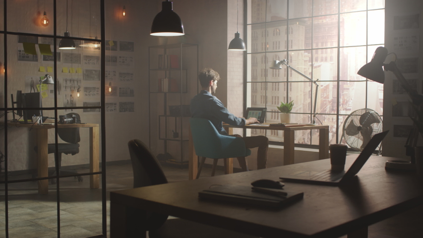 Handsome Creative Developer Works on a Laptop in His Studio. Designing Apps and Social Media Design Structure in His Sunny Loft Office. Modern Urban City View from the Window. Royalty-Free Stock Footage #1030955321