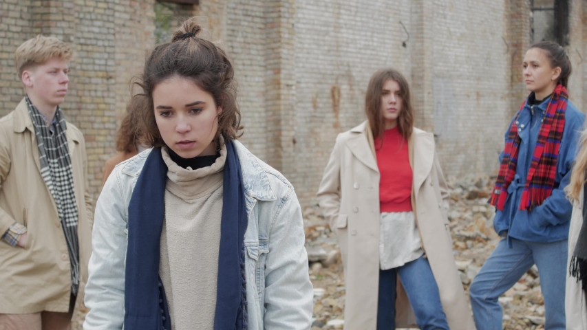 Young brunette woman scared among a group of young people on the ruins. The youth makes a theater etude amid a collapsed brick building Royalty-Free Stock Footage #1030964927
