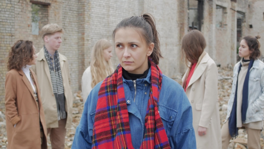 Young woman with scarf scared among a group of young people on the ruins. The youth makes a theater etude amid a collapsed brick building Royalty-Free Stock Footage #1030964939