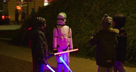 Szczecin, Poland - 12 10 2018: Stormtrooper and fun kids playing with lightsabers wearing star wars costumes on a open street under a lamp post light (editorial)