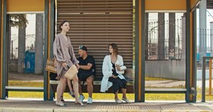 Group of young women waiting the tram. Stylish girls waiting for the public transport while at the modern station outdoors. 4K slow motion raw video footage 60 fps