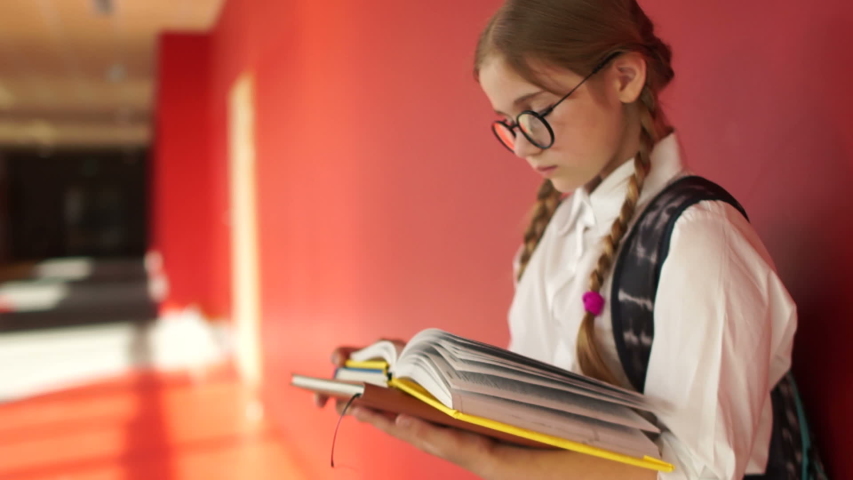 Girl with books and backpack in the school hallway. Back to school