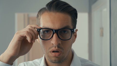 Young man is shocked and surprised. A man in surprise shoots glasses and looks at the camera in surprise.