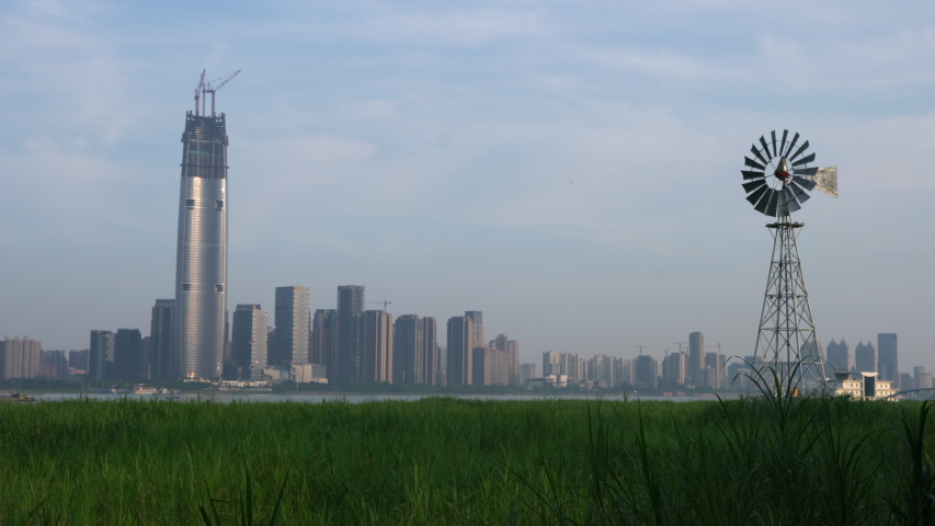 Multi-bladed windpump in middle of Hankou marshland and Wuhan city skyline in background in Hubei China