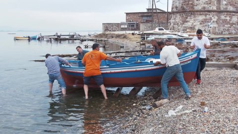 Mytilene, Greece - 12 14 2018: Greek fishermen launch small wooden fishing boat