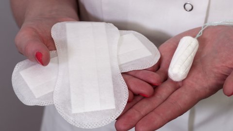 Woman holding menstrual pads and tampon