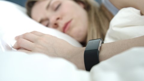 Woman asleep in bed wearing a fitness tracker on her wrist