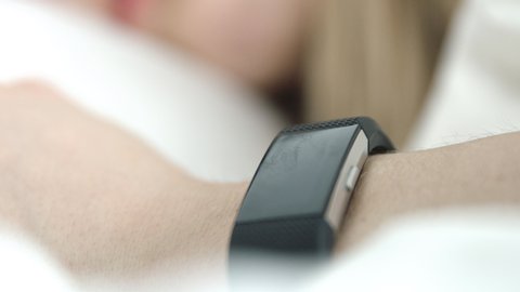 Close up of a woman in bed wearing a fitness tracker on her wrist