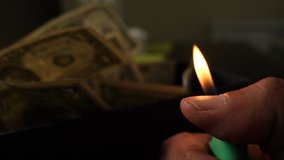 A cigarette lighter emits a flame with dollar bills in a box, money background. Dollars money set With Shallow Dof. Dollars, money close up. - Powered by Shutterstock - Get 15% off with code: PIKWIZARD15
