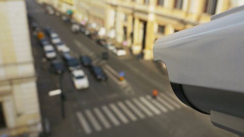 Motorized CCTV surveillance camera above intersection with a traffic light in the center of the city recording traffic flow and people, first person view footage