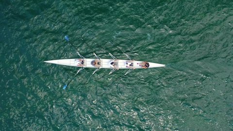 Aerial drone bird's eye view video of sport canoe operated by team of young women in emerald open ocean sea