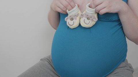 A pregnant woman is played by baby booties.