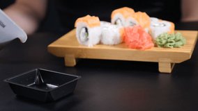 Food video. soy sauce is poured into plate on black background. Beautifully laid sushi set on wooden board. Japanese restaurant sea food menu. Seafood. Healthy eating, diet, dieting concept. hd