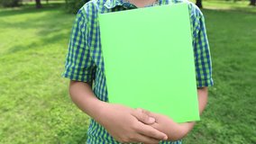 Closeup view of big green paper book in hands of little 10 years old kid. Real time full hd video footage.