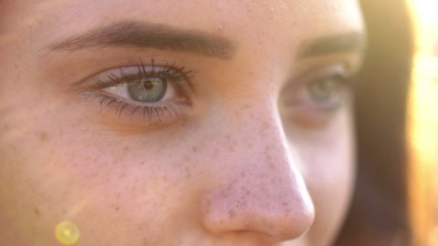 Close up of woman's face at sunset, beautiful green eyes, portrait, outdoor relax sunlight, slow motion.