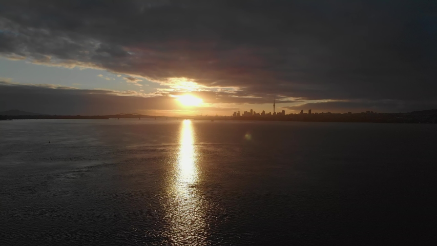 Auckland Harbour with golden sunrise city skyline, New Zealand, Aerial Pull Back