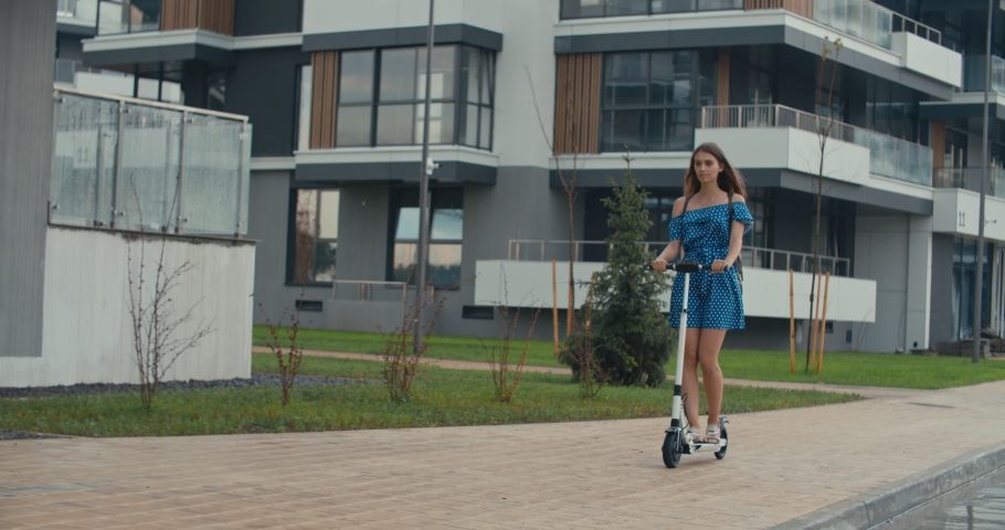 Rainy day. Attractive girl riding the electric kick scooter to work or study. 4K slow motion raw video footage 60 fps | Shutterstock HD Video #1031084285