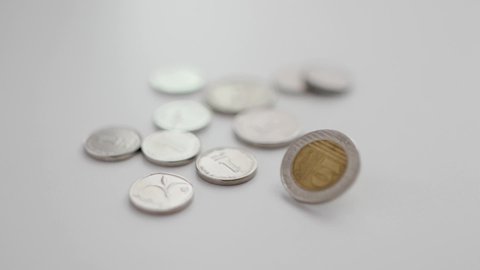 10 Shekel coin spins next to different Israeli coins laid out on table