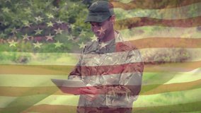 Digital composite of an American soldier typing on a tablet at the park with an American flag waving in the foreground - Powered by Shutterstock - Get 15% off with code: PIKWIZARD15