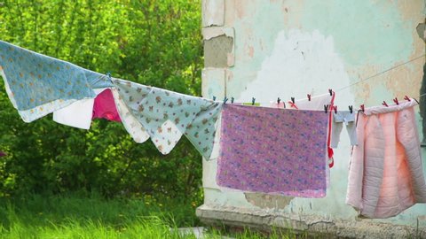 Clothes Hanging on the Clothesline Outdoor Near Run Down House. Wash clothes on a rope with clothespins. Housework and Housekeeping Concept