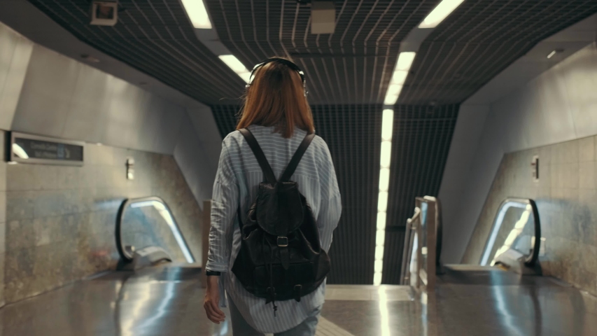 Modern young girl climbs the top of the stairs. Underground crossing. A student goes to the subway.