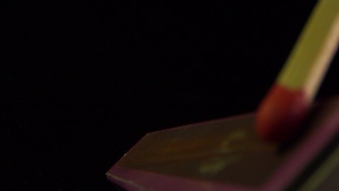Beautiful match-fire Ignition and burning in slow motion of a match on the side of the box, black background.