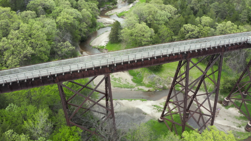 Cowboy Trail, a bike trail converted from an old railroad line in northern Nebraska crosses a stream valley on a long trestle, earial view of spring scenery