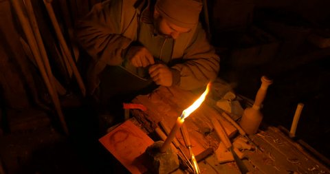 A wood carver illuminated by candlelight at Villongo (Italy) on January 6, 2015