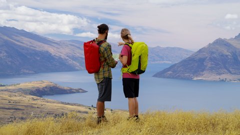 Active Caucasian adventure travelers enjoying their hiking and planning tour reading map of Mount Aspiring Lake Wakatipu New Zealand RED WEAPON