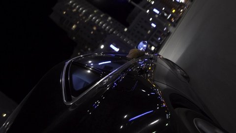Black moder car moving in the city streets at night with car LED lights shimmer in different colors. Footage. The car driving against the background of buildings in the evening.