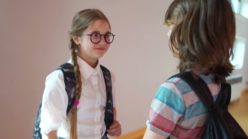 School love. The boy and the girl are talking in the school hallway, the boy comes closer and hugs the girl, they embarrassedly leave