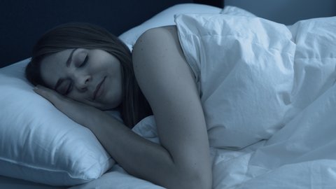 Peaceful woman in bed at night enjoying a clam and restful nights sleep.