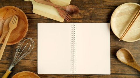 A male hand open recipe cooking book  paper 3 page  with cooking equipment on the wooden desk, top view and overhead shot use for blank template book mock up to add any text content for cuisine cookin