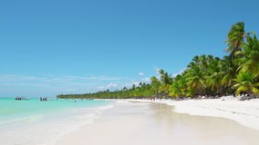 Punta Cana white sand beach video 4K. Caribbean sea of Atlantic ocean. Palm trees, blue sea and sky background. Best white sand beach of Punta Cana Dominican Republic. Summer white sand beach resort 