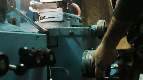 worker hands rotate metal lathe round lever grinding detail