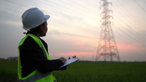 Woman electric Engineering working at High-voltage tower site on sunset
