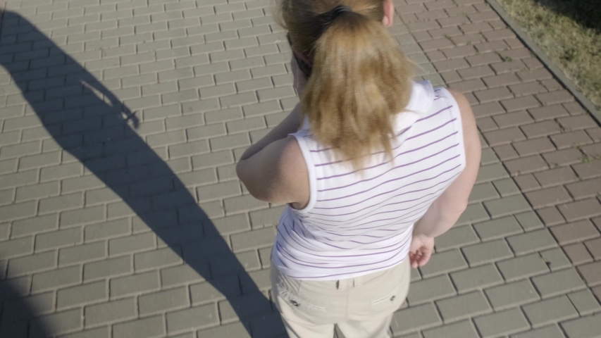 girl drops smartphone on sidewalk in city park. phone falls and breaks into pieces.