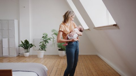 Loving Mother Holding Sleeping Newborn Baby At Home In Loft Apartment