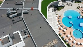 Aerial video shooting. Swimming pool with clear blue water on site. Men and women relax at the resort. Circular panorama. Sunny day.