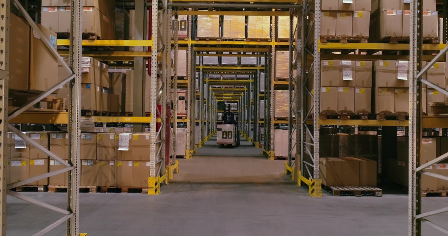 The forklift carries boxes with products at the warehouse, forklifts traveling between the rows in the warehouse. Industrial interior Royalty-Free Stock Footage #1031184227