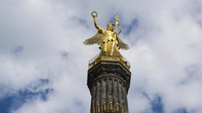 Siegessaule or Victory column with golden statue in Berlin, Germany. Time lapse of clouds passing behind monument. Major tourist spot and sight in city. Famous landmark and popular tourist attraction.