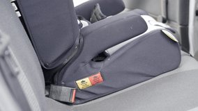Man installing a child safety car seat into an automobile. SIDE ANGLE. CLOSE UP.