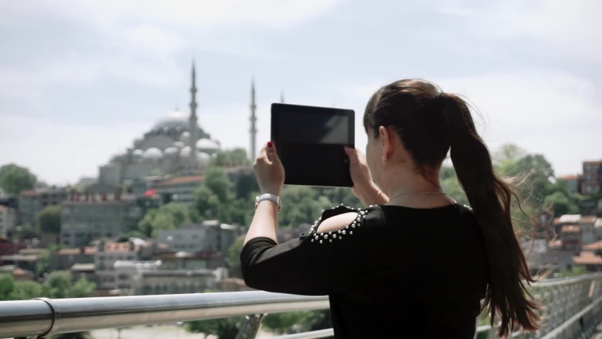 A tourist girl takes video of a beautiful landscape of the city and bright sights