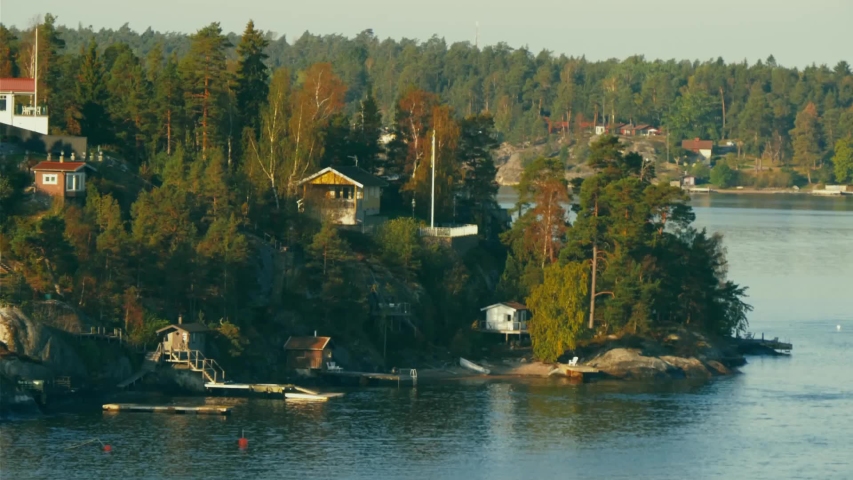An island with houses, cottages, and cabins built onto the side of a hill that drops into the water.
