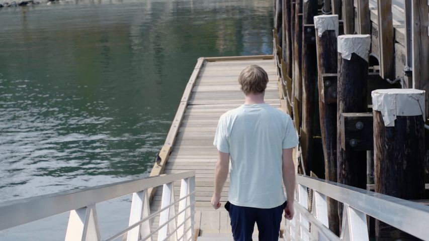 Slow Motion Man Walking Down Ramp On Wooden Dock In Marina On The Ocean