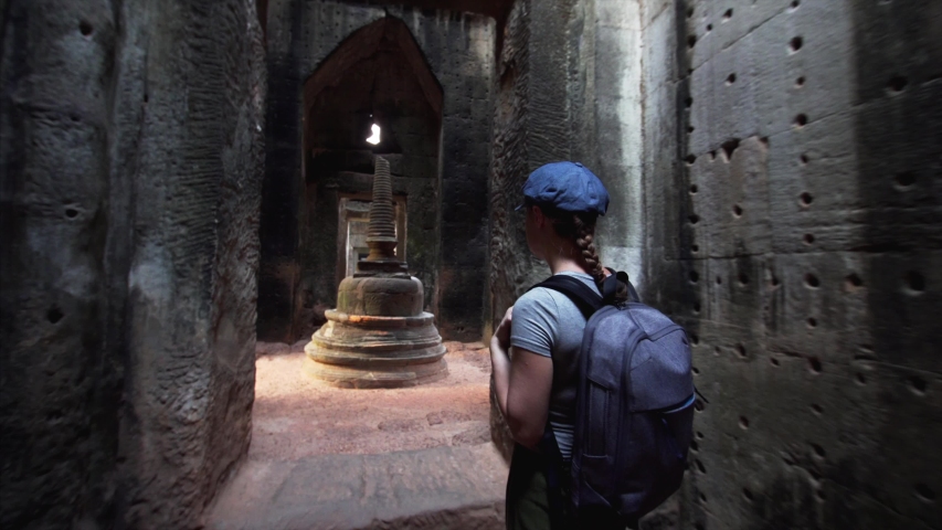 Caucasian woman with backpack is exploring Preah Khan and central stupa. It