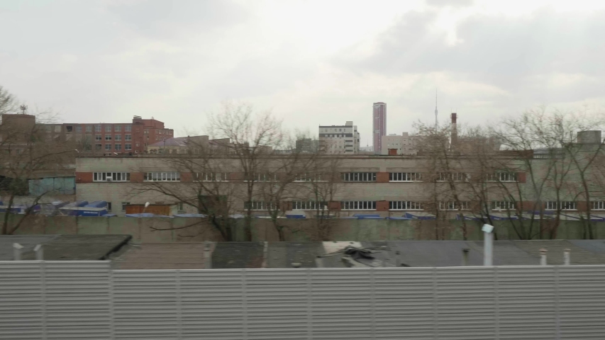 View of high and short buildingns of industrial area of Moscow from window of moving train.