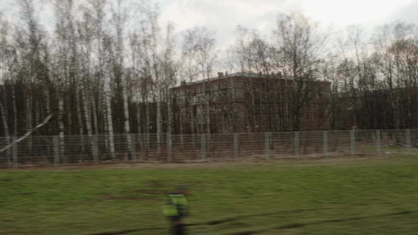 View of Losiniy Ostrov Park from window of moving train. Forest near city. Dull weather in Moscow.