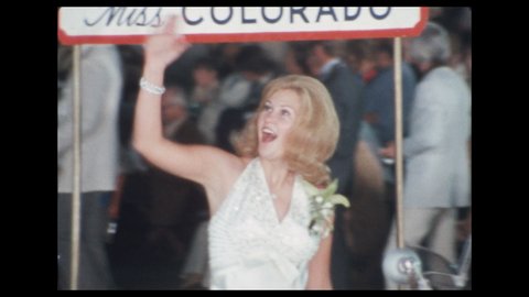 1970s: Pageant contestant waves from back of decorated car in parade. Marching band plays instruments in parade. Women dance with batons in parade.