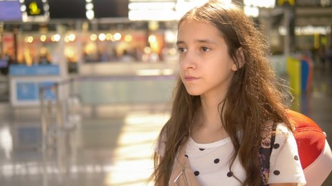 Portrait of a teenage girl standing at the airport. The girl looks into the camera and smiles. Blur background